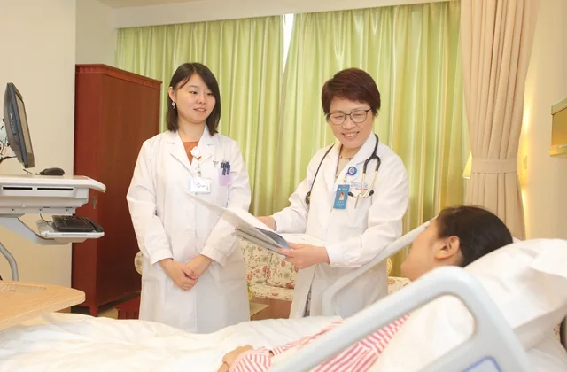 Deux médecins chinoises visitant une patiente dans une chambre d’hôpital